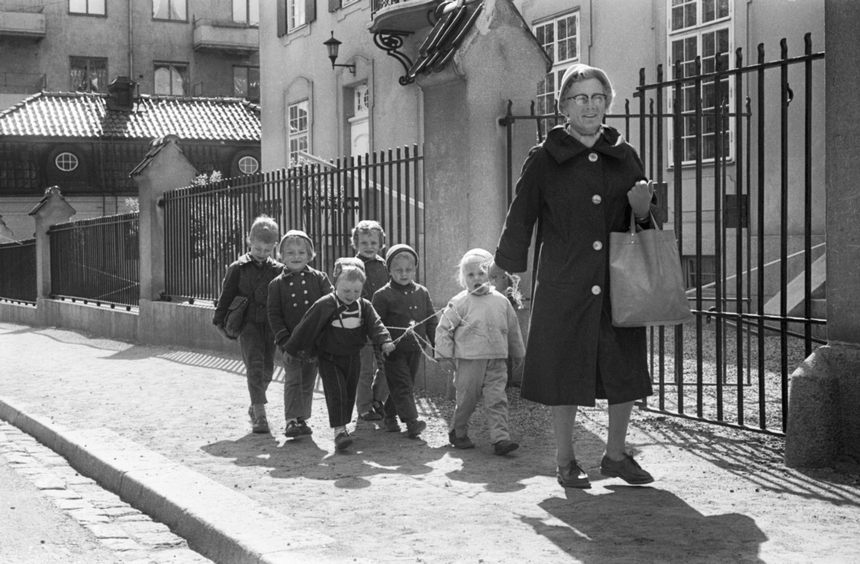 Kvinna på promenad med sex barn sammanhållna med ett snöre