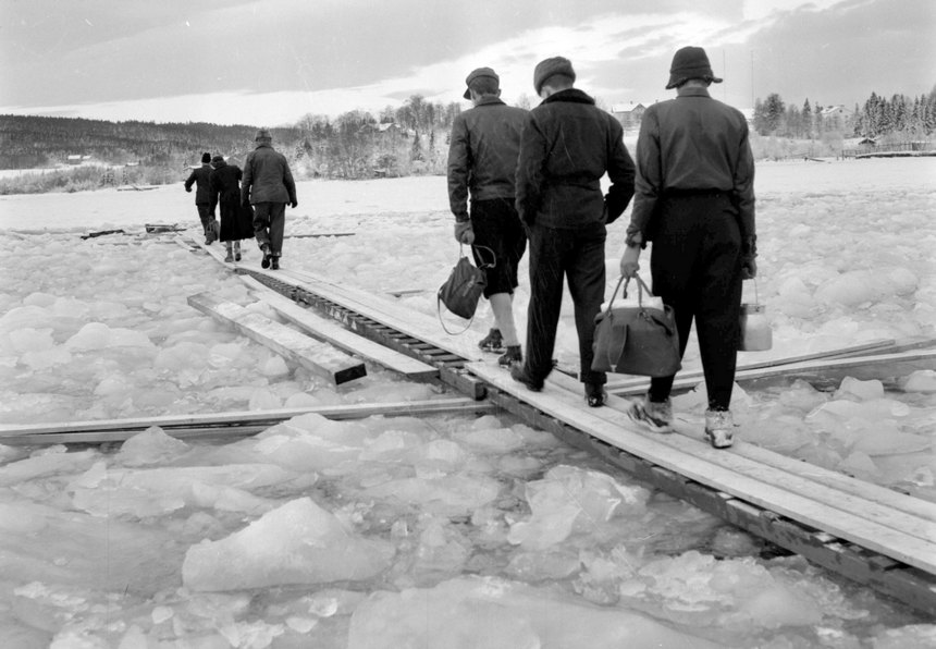 Sex personer går över en träspång som ligger på isen