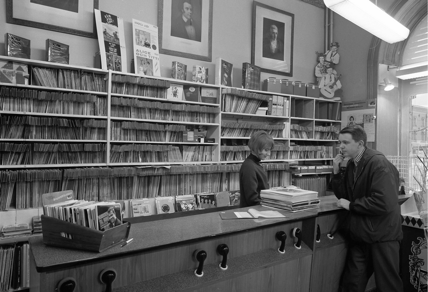 Interiör från skivbutik. I bakgrunden syns en hylla med en stor mängd skivor. Två personer står vid en disk