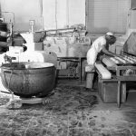 Interiörbild från bageri, två personer varav en arbetar med degämnen vid en maskin