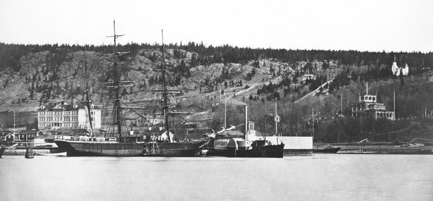 Vy över norra sidan av Sundsvalls hamn. I förgrunden syns två båtar och i bakgrunden Norra stadsberget, byggnaden Tivoli och lasarettet